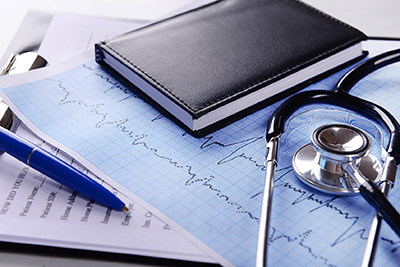Stethoskop auf EKG-Auswertung mit Notizbuch und Stift
